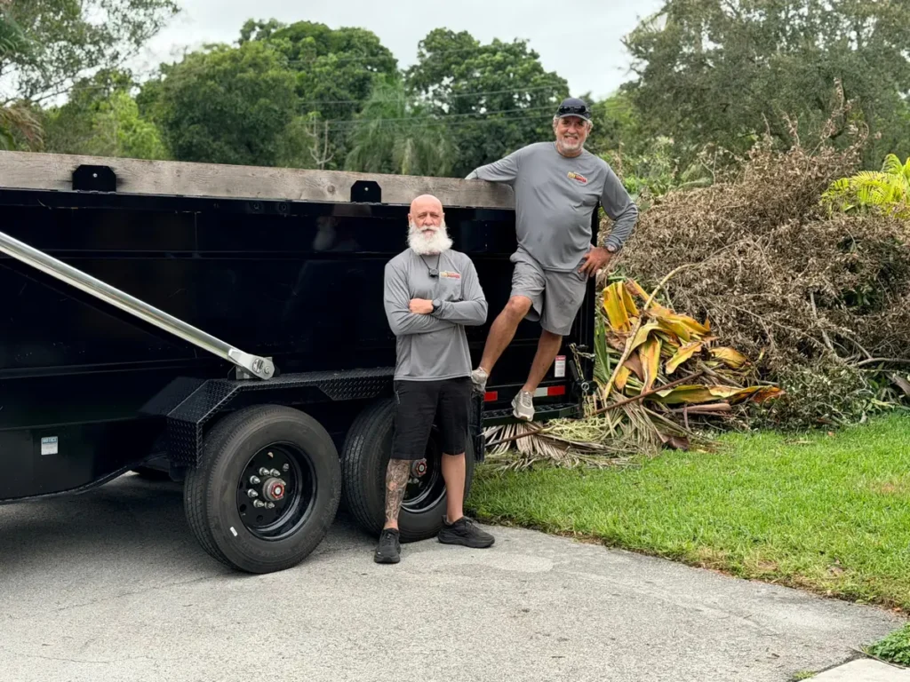 Junk removal team with dump trailer during yard waste cleanup