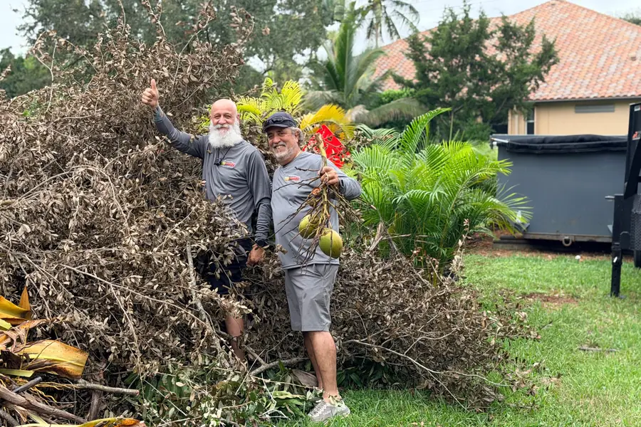 Crew standing on a yard debris pile ready for removal in Broward County